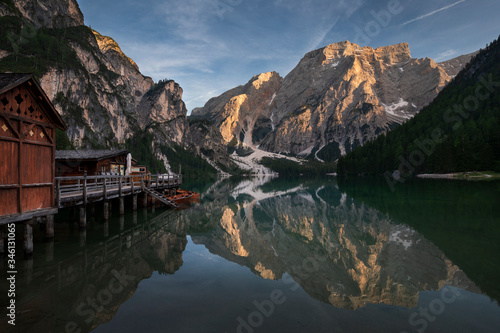 Boat house with boats at Lake Prags during sunset in the Dolomite Alps, refelction of the mountains on the water surface, South Tyrol Italy.