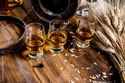 Obraz na płótnie Small tasting glasses with aged Scotch whisky on old dark wooden vintage table w