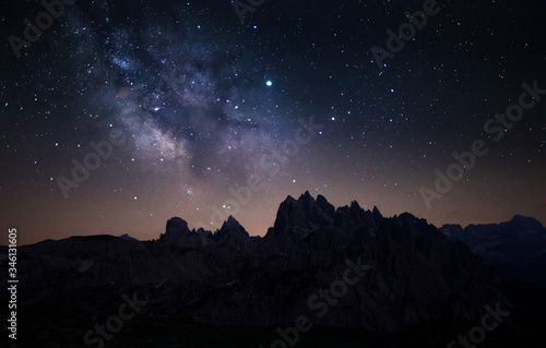 Mountain silhouettes with milky way and stars in the night sky at Three Peaks in the Dolomite Alps, South Tyrol Italy.