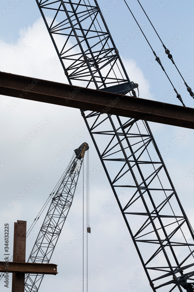 Consruction work with large steel structure and industrial cranes against a semi blue sky