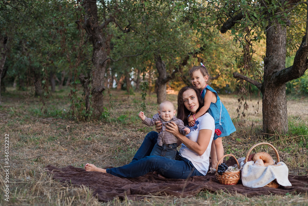 Picnic in the apple garden. Little girl hugs mom. Young mother with children in autumn garden Picnic in the apple garden. Little girl hugs mom. Young mother with children in autumn garden