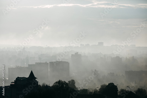 Silhouettes of city buildings in morning light in fog.