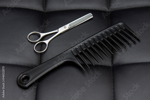 Hairdresser tools. Scissors and comb on a leather background