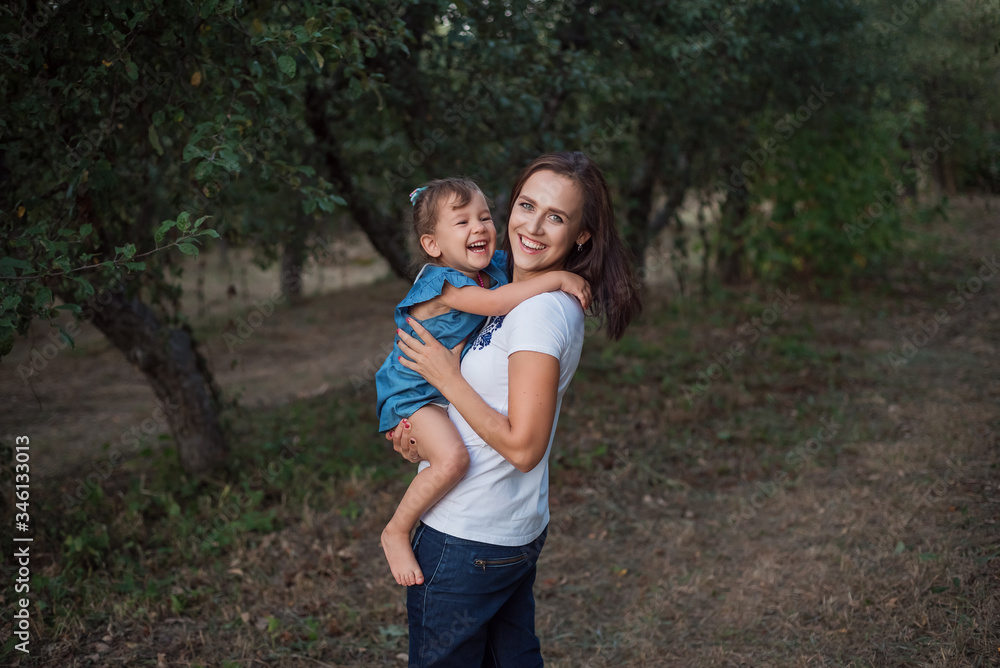 Fototapeta premium A stylish family in an apple garden in the fall. Emotional family portrait