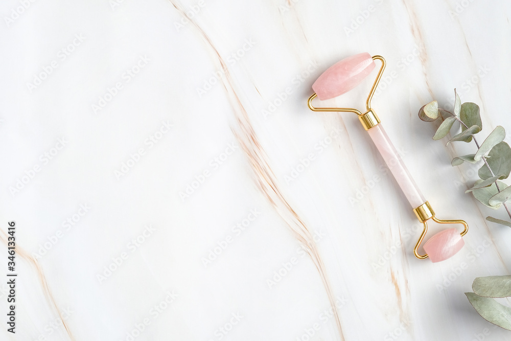 Rose quartz face roller and eucalyptus leaf on marble background, top view. Face massage tool, beauty treatment and facial skin care concept - obrazy, fototapety, plakaty 