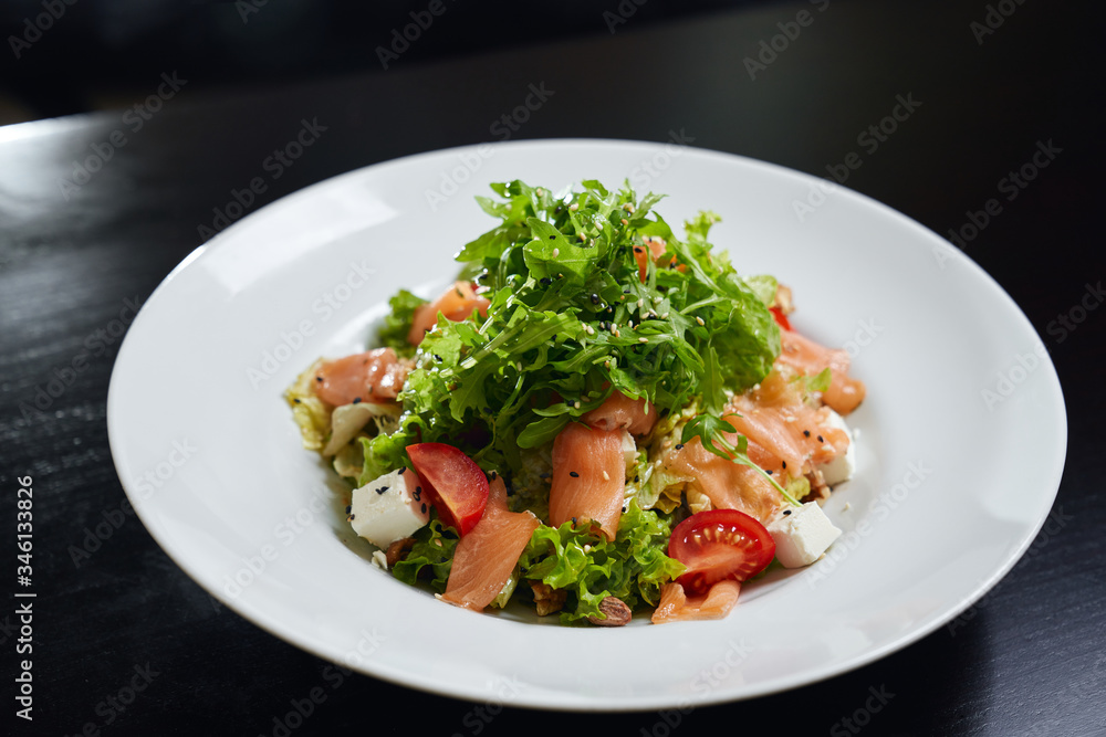 Fresh salad with raw salmon on plate.