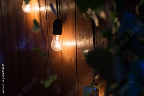 The lamp burns near a wooden wall. photo