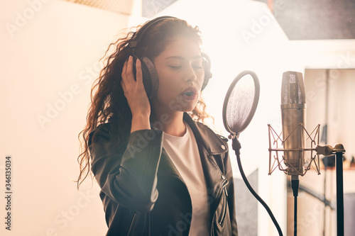 Pretty female singer recording in music studio photo