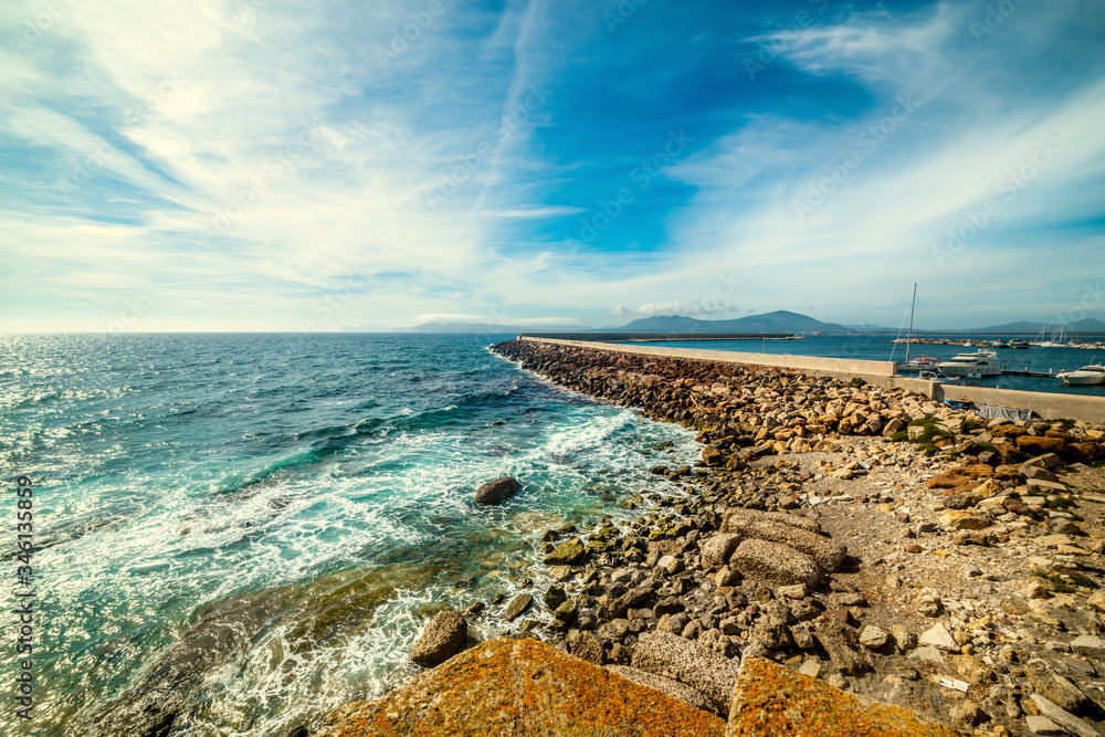 Breakwater in Alghero seafront under a cloudy sky Breakwater in Alghero seafront under a cloudy sky