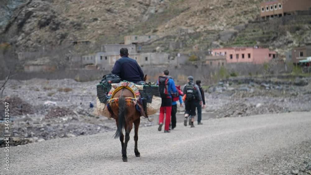 Man on donkey carrying stuff and trekkers in small village at the Moroccan Atlas.
Mid angle, following movement, slow motion, HD. Man on donkey carrying stuff and trekkers in small village at the Moroccan Atlas.
Mid angle, following movement, slow motion, HD.