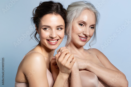 Two smiling women of different ages looking at different side holding hand closeup portrait. 