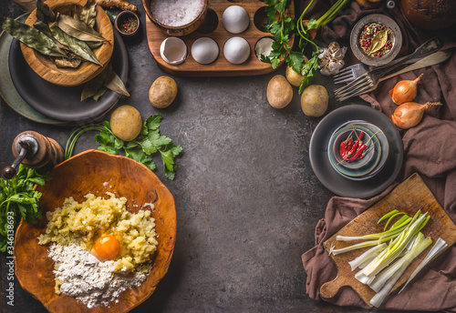 Rustic food background with preparation of potato dough . Mashed potatoes with egg and flour in wooden bowl . Dark kitchen table with organic ingredients for tasty home cooking. Frame. Top view.