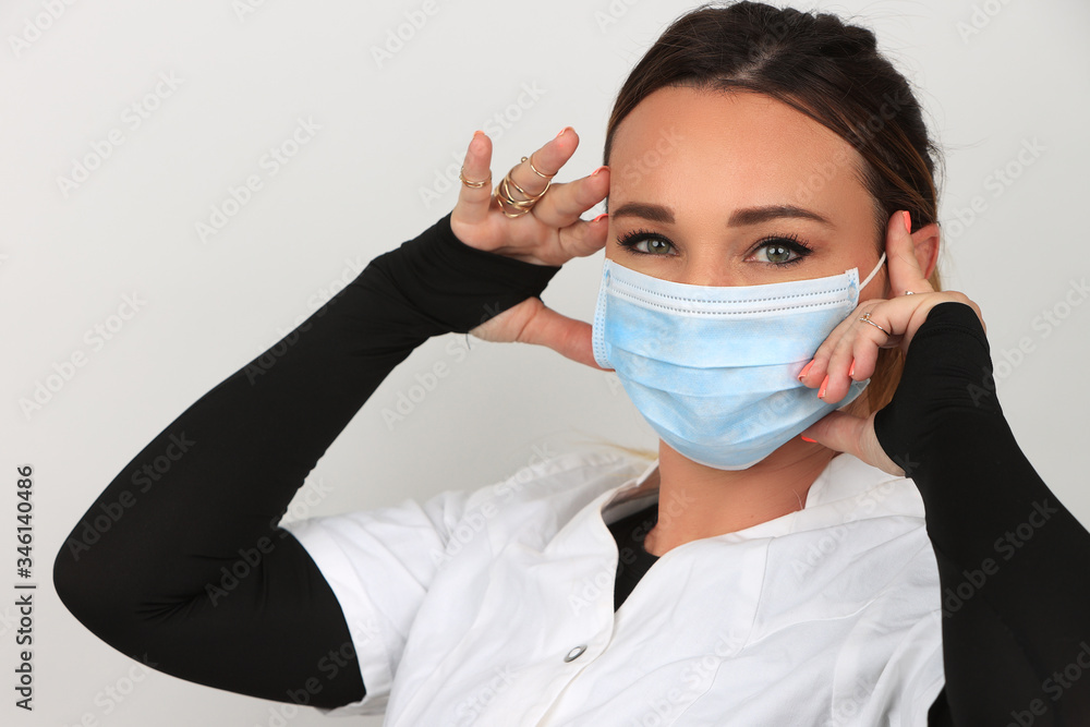 Jeune femme avec un masque chirurgical pour se protéger des virus sur fond uni blanc Jeune femme avec un masque chirurgical pour se protéger des virus sur fond uni blanc