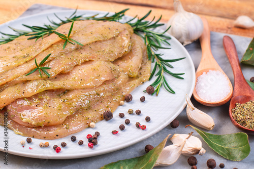 Sottilissime in a white marinade on a white plate with a branch of razmarin and spices with wooden spoons, garlic on a marble cough board on a wooden background. photo