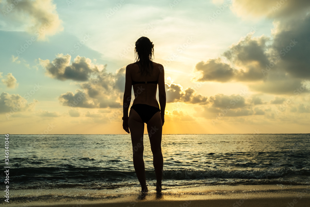 Happy carefree woman in bikini enjoying beautiful sunset