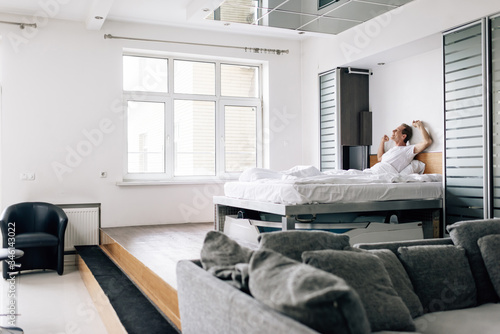 selective focus of happy man stretching in modern bedroom
