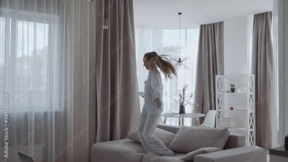 girl having fun and jumping on sofa In the interior of the apartments
