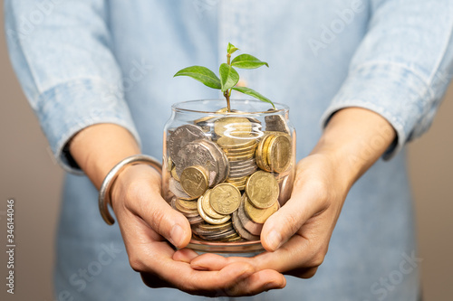 фотографія Woman Hold a Plant glowing in savings coins