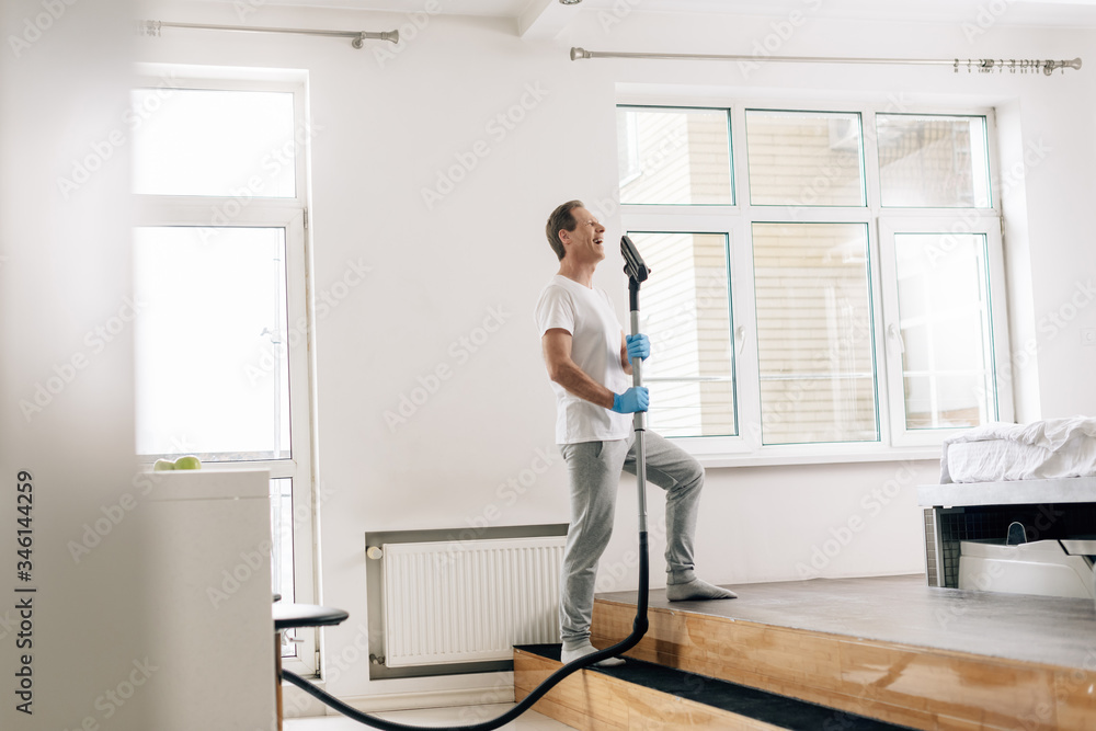 selective focus of happy man holding vacuum cleaner selective focus of happy man holding vacuum cleaner