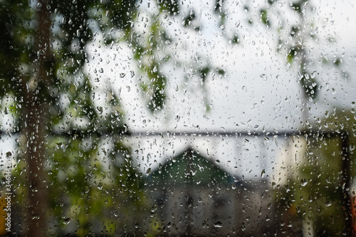 Raindrops on window pane. Blurred background outside the window in the rain.