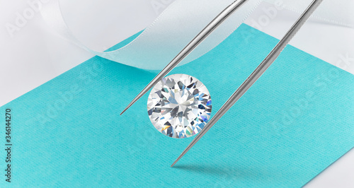 Loose Diamond on Background Held in Tweezers 