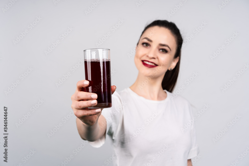 Girl with bright appearance, she's holding a glass with red juice and smiling, concept advertising juice Girl with bright appearance, she's holding a glass with red juice and smiling, concept advertising juice