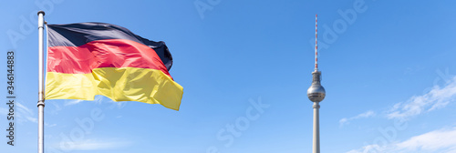 Flag of Germany and TV Tower of Berlin with blue sky, panoramic picture 