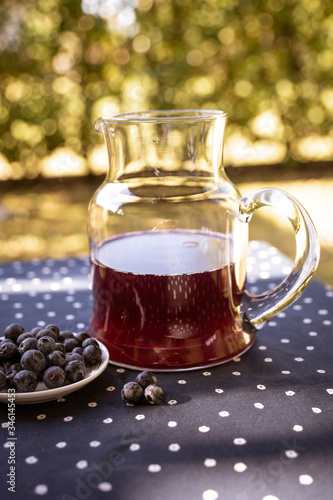 carafe with blueberry juice on a table in the garden