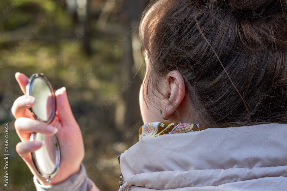 Obraz premium A woman looks in the mirror against the background of the forest
