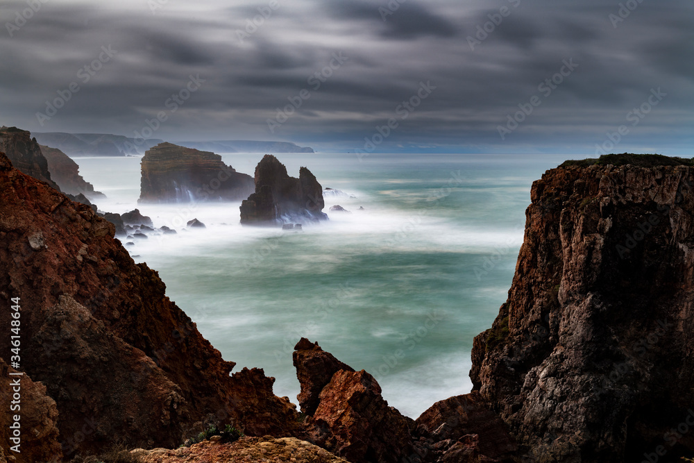 Scenic view of the coastline along Carrapateira with the rock formations and waves crashing during a storm, in Algarve, Portugal