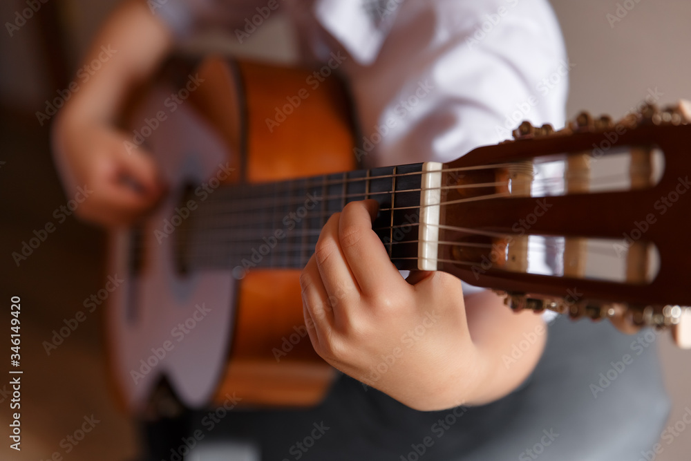 a boy in a shirt plays the guitar