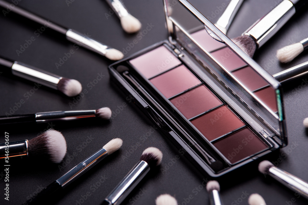 Cosmetic palette and face shadow with brushes lies on a black background Cosmetic palette and face shadow with brushes lies on a black background