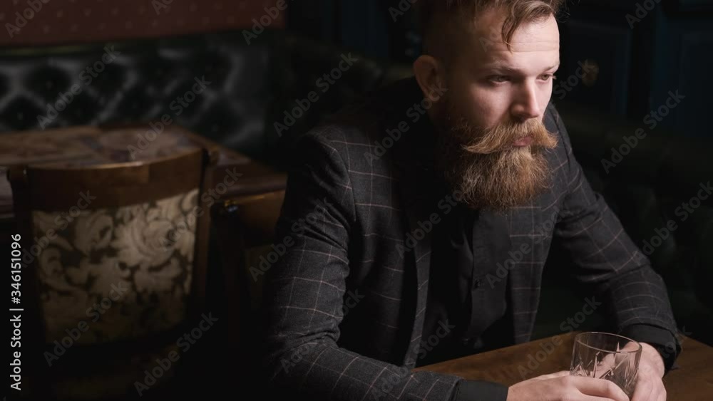 man drinks alone at table,with beard and mustache in suit drinks from glass of whiskey, Bourbon, rum, loneliness and depression, Caucasian, concept of alcoholic recreation man drinks alone at table,with beard and mustache in suit drinks from glass of whiskey, Bourbon, rum, loneliness and depression, Caucasian, concept of alcoholic recreation