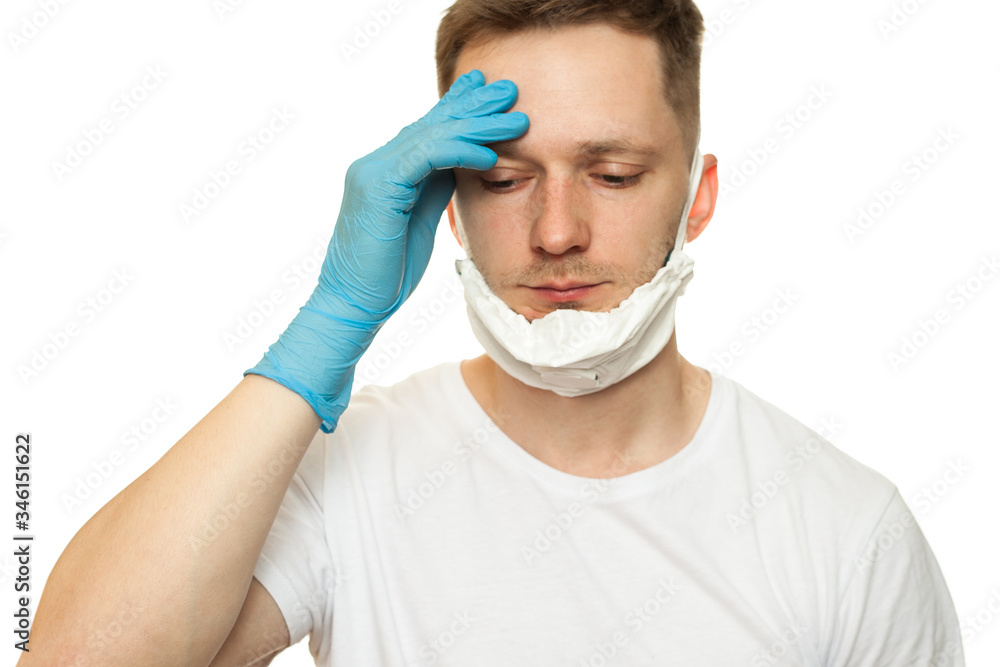 Tired sad surgeon doctor in hygienic mask and blue gloves in depression upset and holds his head. Isolated on white background. Protection against contagious disease, coronavirus. Covid, quarantine