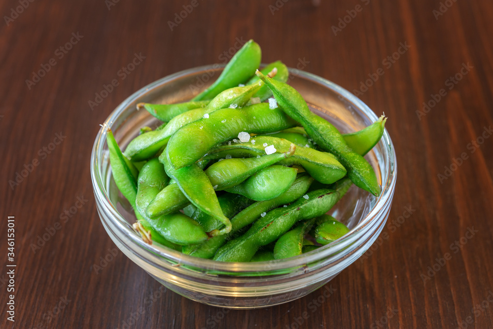 Green beans in a glass round plate on a wooden brown table. Close-up. Green beans in a glass round plate on a wooden brown table. Close-up.