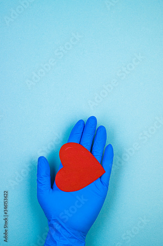 red heart in hand in a blue medical glove on a blue background. background for the day of the medic