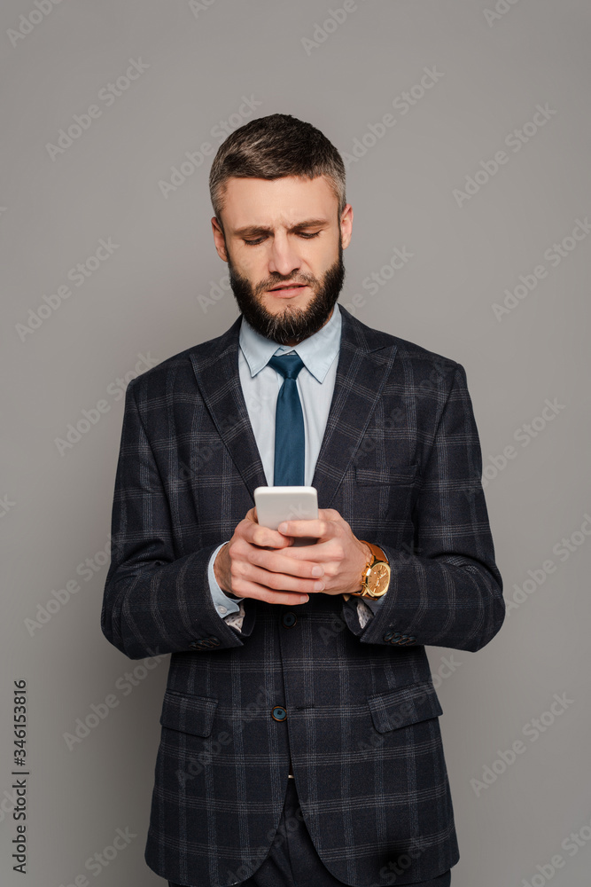 handsome bearded businessman in suit using smartphone on grey background handsome bearded businessman in suit using smartphone on grey background