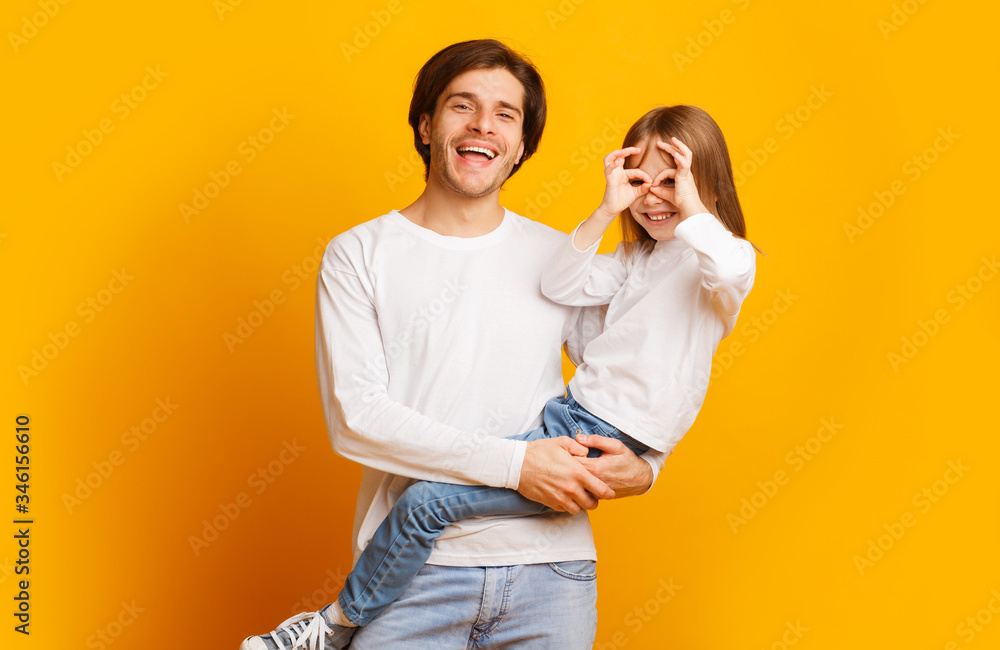 Playful girl and dad having fun on yellow background - obrazy, fototapety, plakaty 