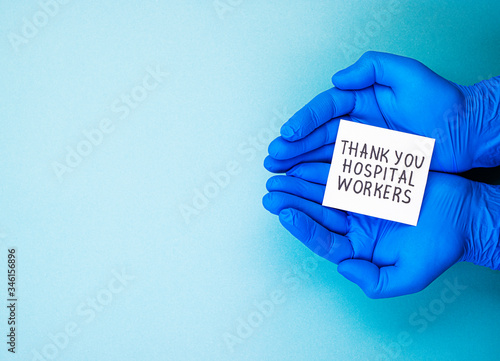 Hands in blue medical gloves holding the inscription thank you to the hospital workers, top view. thanks to the medical staff, doctors and nurses