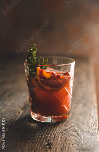 Old-fashioned cocktail with blood oranges and thyme on the rustic background. Selective focus. Shallow depth of field. 