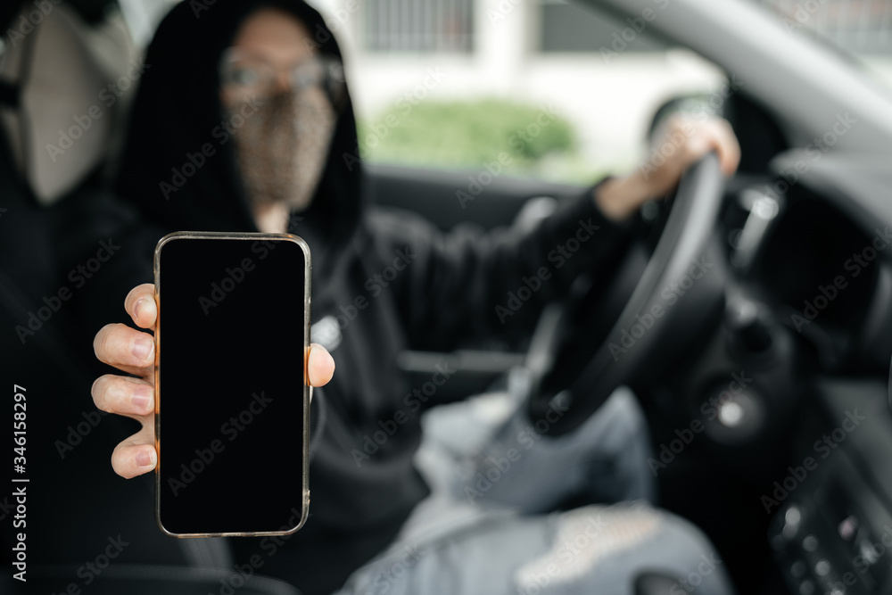 A woman driver in a masked car shows a smartphone screen with a digital pass to travel through the city. The concept of the coronovirus epidemic. A woman driver in a masked car shows a smartphone screen with a digital pass to travel through the city. The concept of the coronovirus epidemic.