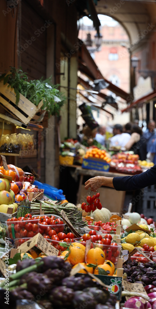 Frutería en mercado callejero de Bologna (Emilia Romagna, Italia) Mujer escoge tomates