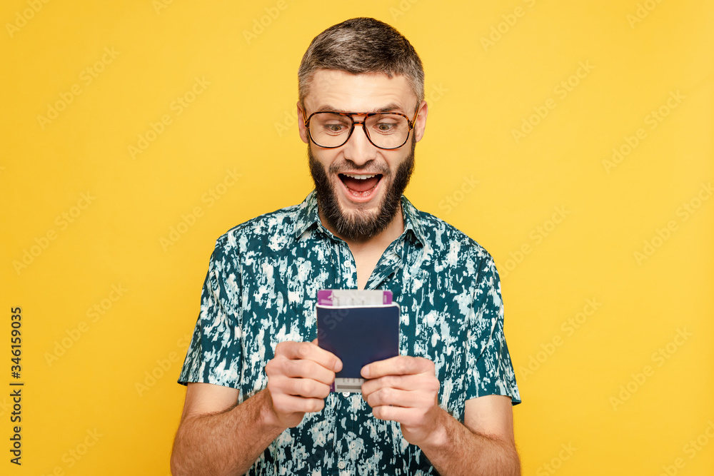 excited bearded guy in glasses with air ticket and passport isolated on yellow excited bearded guy in glasses with air ticket and passport isolated on yellow