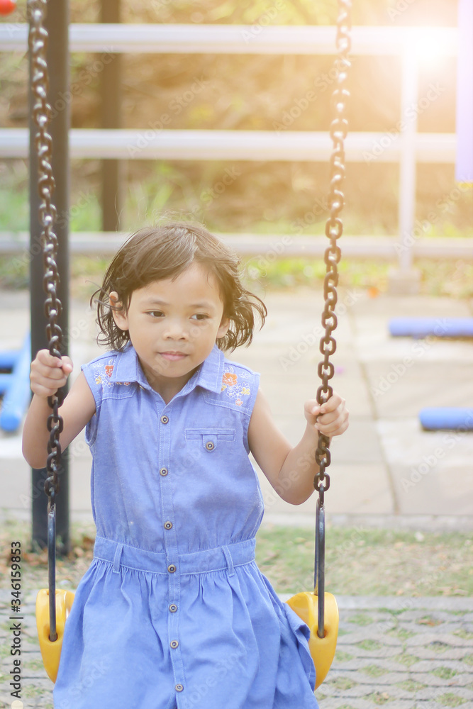 The girls play on the playground sit on the swing with fun and happiness.