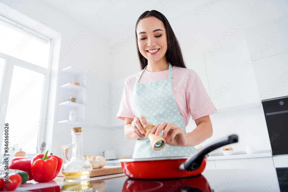 Portrait of her she nice attractive lovely focused busy cheerful careful housewife making delicious meal lunch adding spices weight loss lifestyle in modern white light interior style kitchen