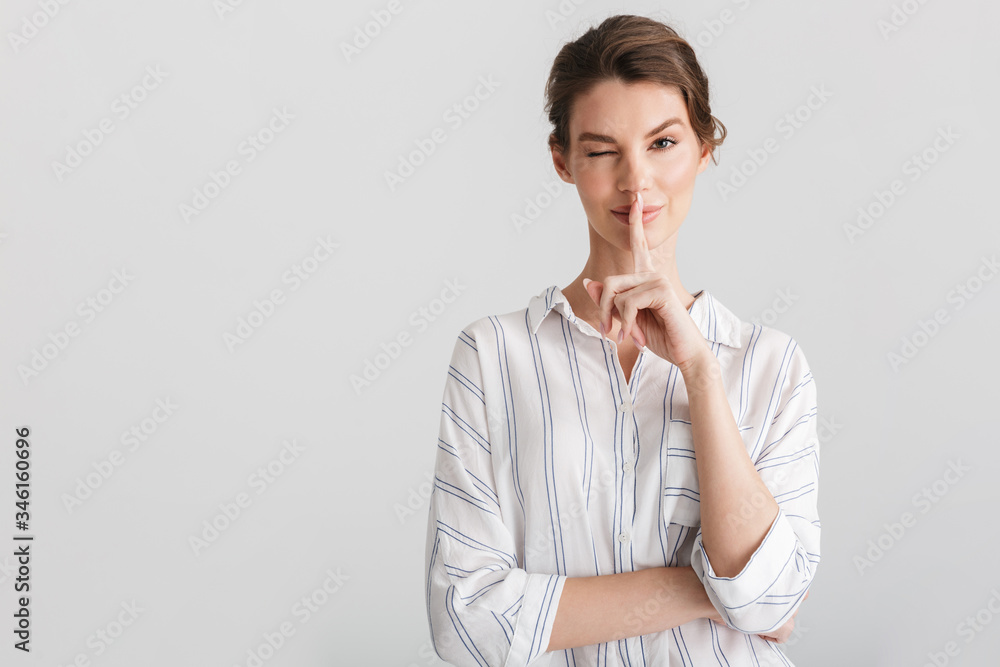 Image of pleased nice woman showing silence gesture and winking Image of pleased nice woman showing silence gesture and winking