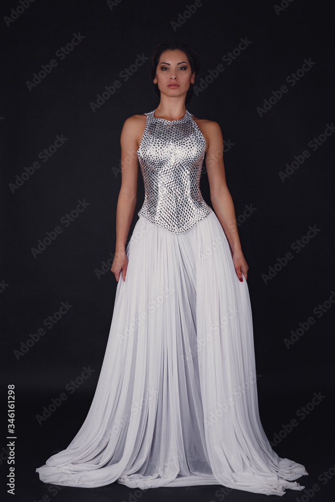 Pretty girl posing in a fashion dress over black background Pretty girl posing in a fashion dress over black background
