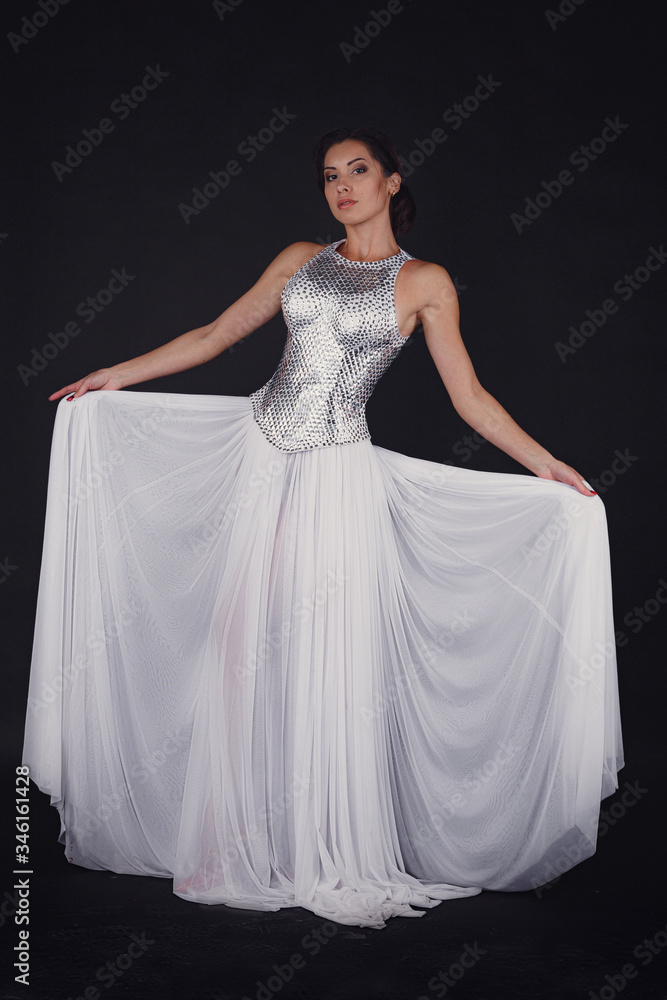 Pretty girl posing in a fashion dress over black background