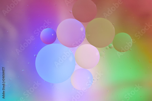 Top view movement of bubbles in the liquid. Oil surface multicolored background. Fantastic structure of colorful bubbles. Colorful artistic image of oil drop floating on the water