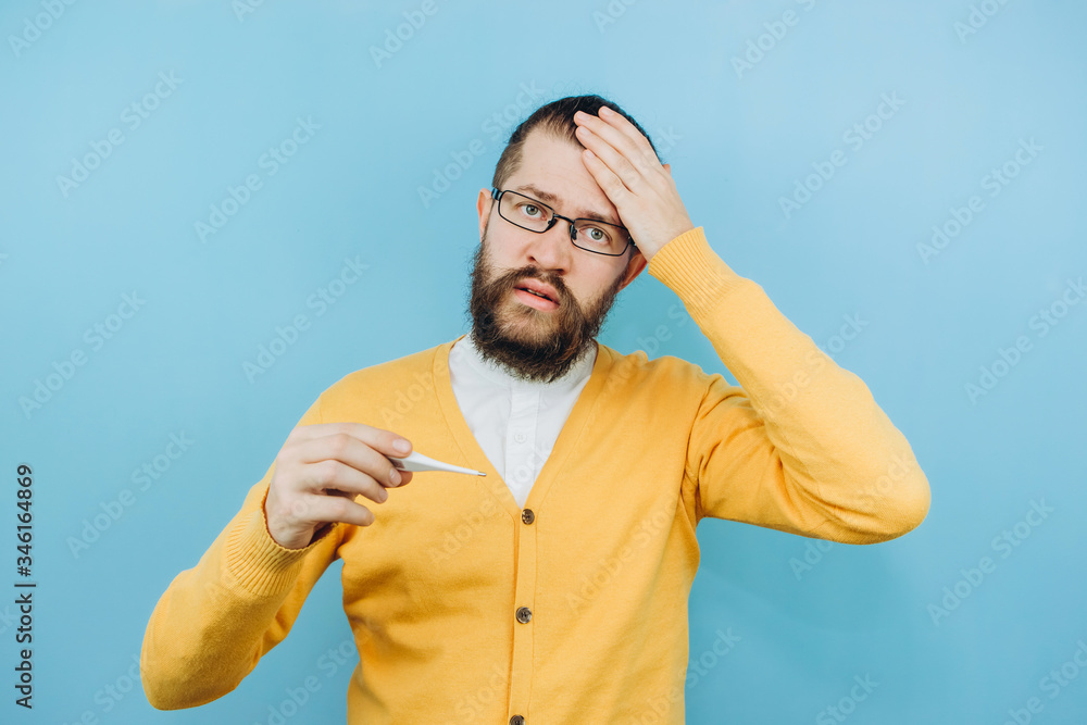 Naklejka premium The guy with the symptoms of a grit on a blue background. A man with a cough, a headache, a fever. Symptoms of coronavirus. COVID 2019 Epidemic